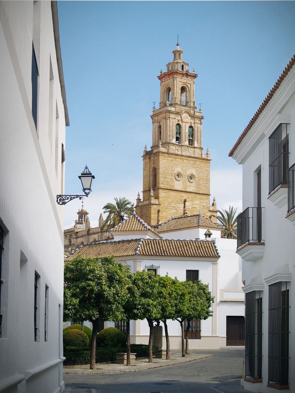 Una torre de campanario de estilo arquitectónico español, con una estructura alta y esbelta, rematada por un techo de tejas.